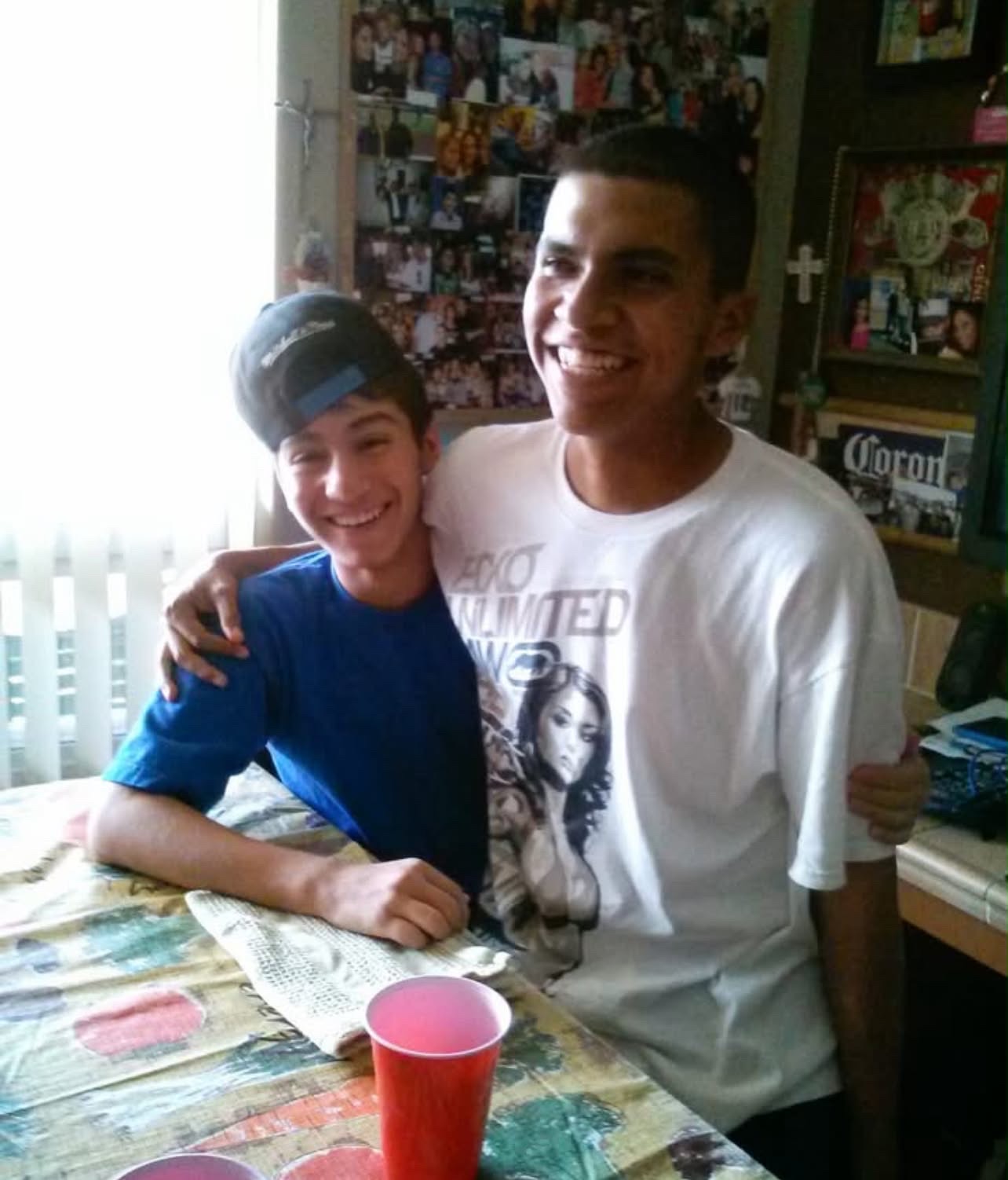 Mando with his arm around a friend at the kitchen table
