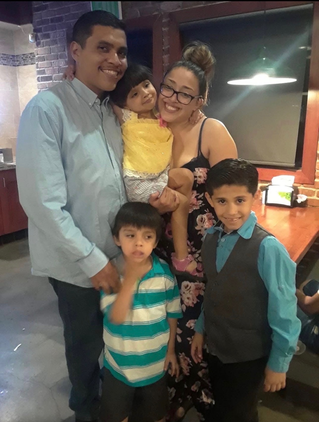 Mando in a light blue shirt standing with family at a restaurant table