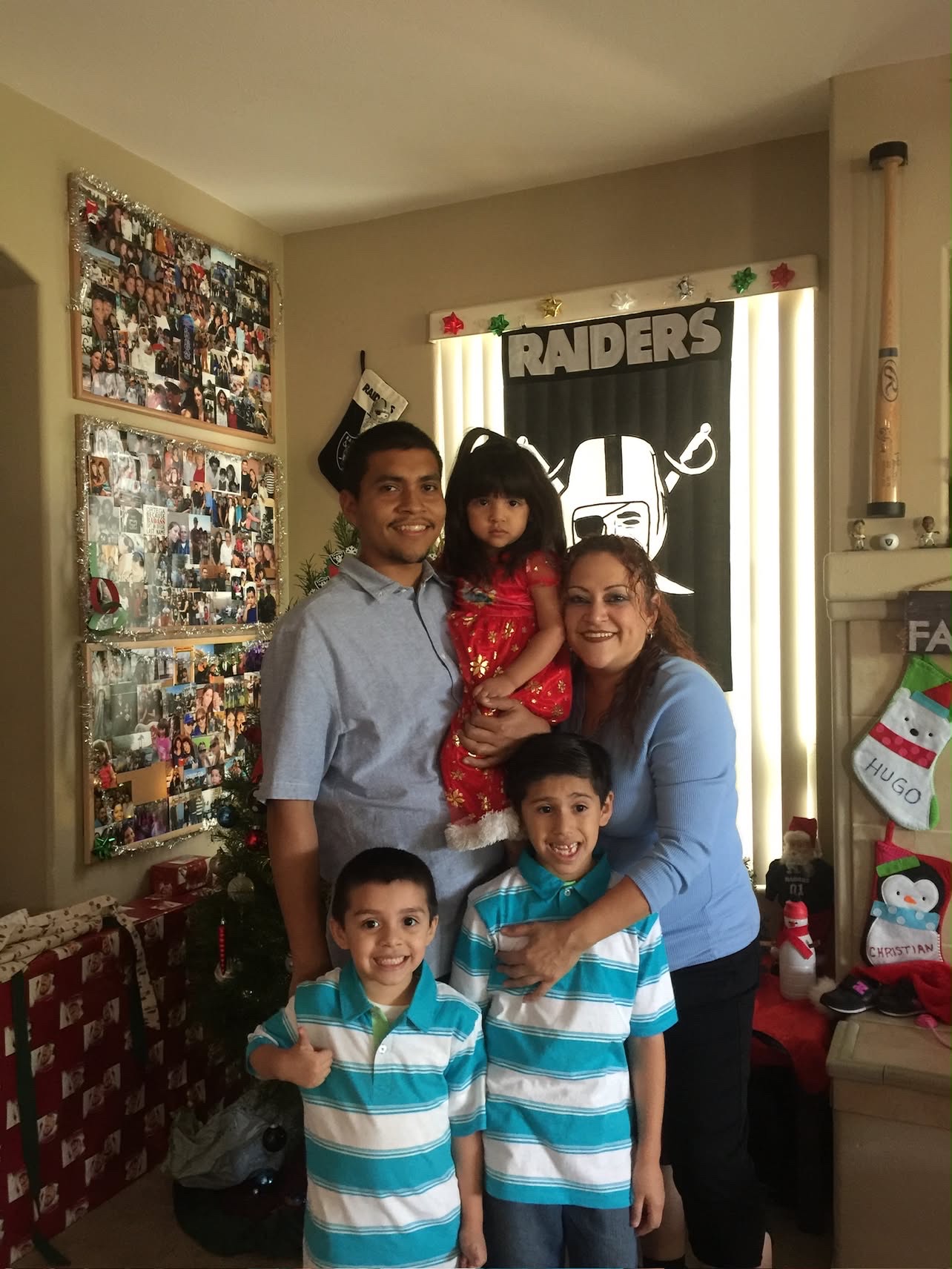 Mando holding a toddler girl at Christmas with family in front of a decorated tree