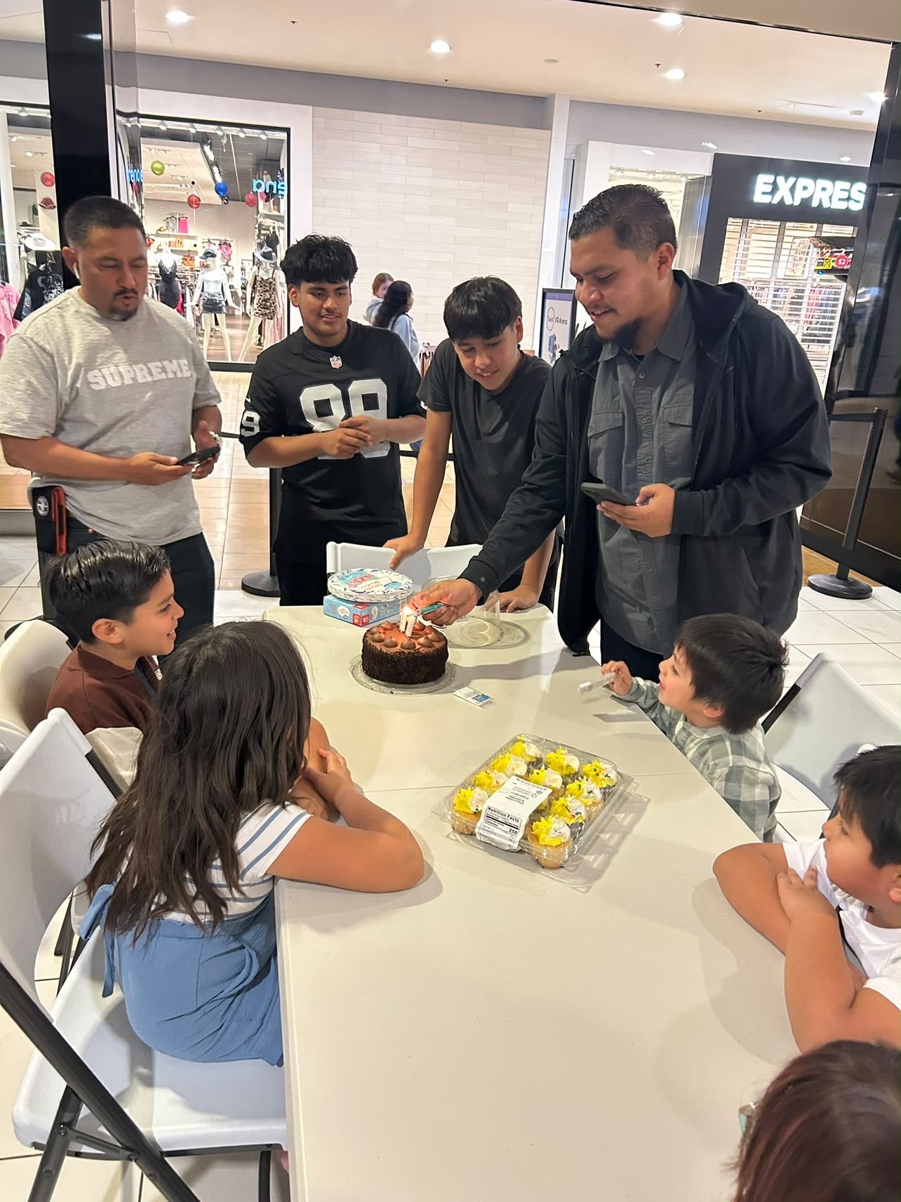 Mando lighting birthday candles surrounded by family
