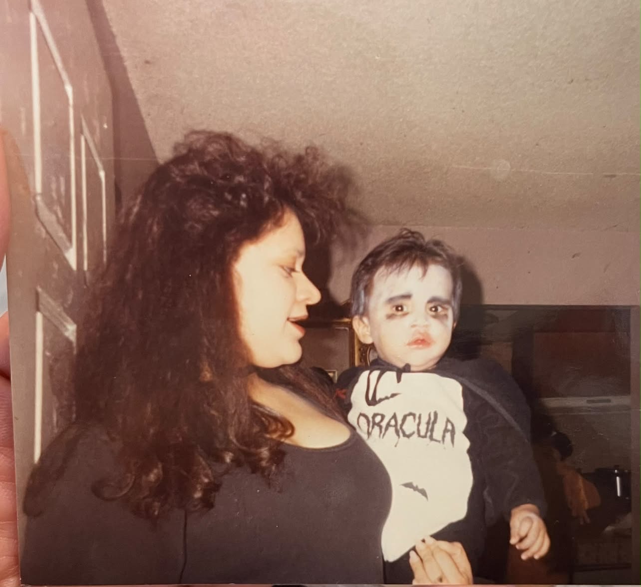 Mando as a little boy in a Dracula Halloween costume, held by his mother