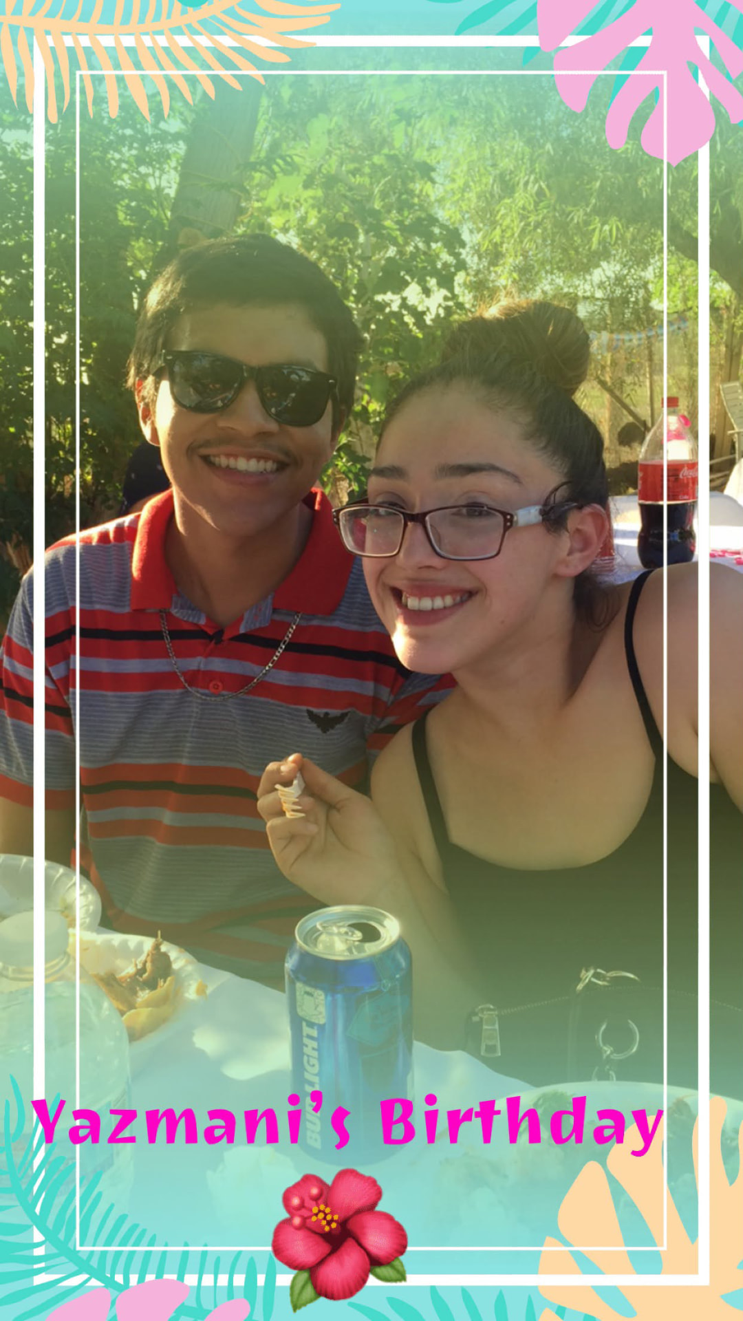 A young man in sunglasses and a woman seated close together at an outdoor birthday gathering
